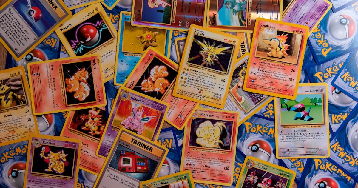 A collection of colorful Pokemon trading cards spread across a flat surface before being sorted into storage
